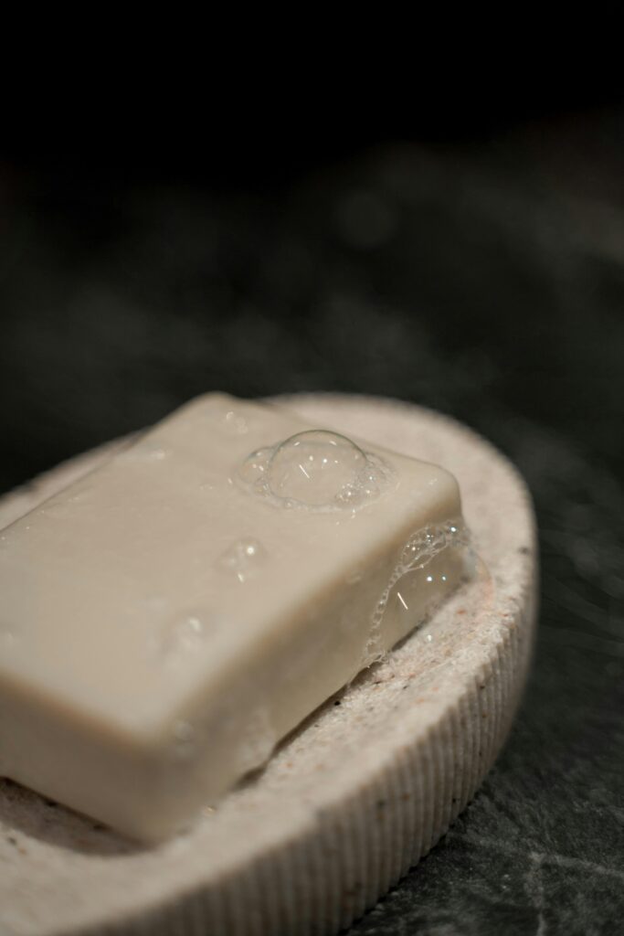 Close-up of a soap bar with bubbles on a stone holder, emphasizing cleanliness and spa aesthetics.